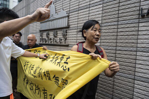 Miembros de la Liga de Socialdemócratas sostienen una pancarta frente a los Tribunales de Magistrados de West Kowloon en Hong Kong, el jueves 30 de mayo de 2024, antes de las sentencias en un caso de seguridad nacional.  lee el letrero "El ejercicio de los derechos constitucionales no es un delito." (Foto AP/Chan Long Hai)