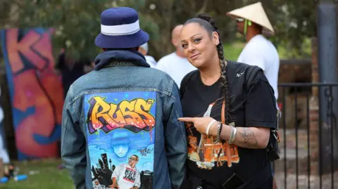 Beck Rushby Spice señala una chaqueta artística con graffiti que dice Ross