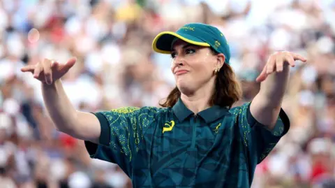 Getty Images Raygun viste una camisa y un sombrero, extendiendo sus brazos frente a ella.