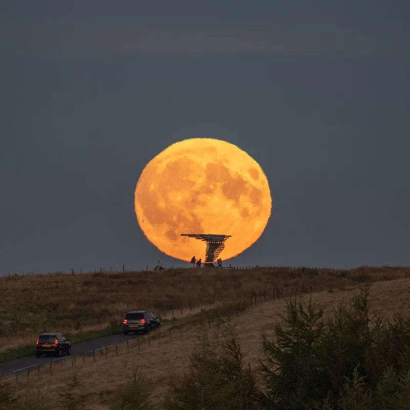 Imagen de la Luna de la Cosecha el 18 de septiembre de 2024 por Lee Mansfield sobre la escultura Singing Ringing Tree, Burnley, Lancashire, Reino Unido. El Singing Chime Tree es una escultura acústica impulsada por el viento que se asemeja a un árbol ubicado en el paisaje de Pennine Hills con vistas a Burnley, Lancashire.