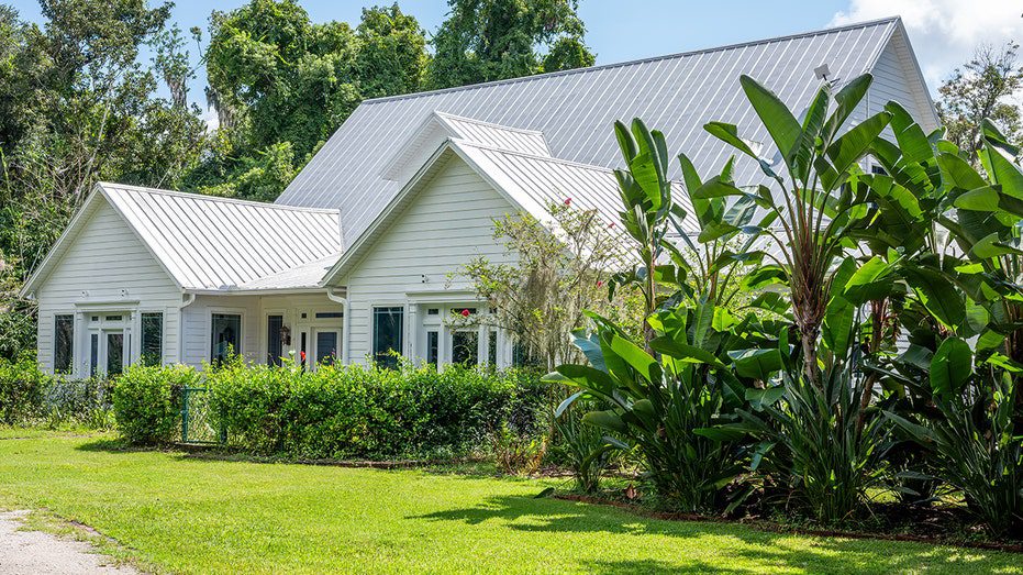 El exterior de la casa está bordeado de césped verde y varias plantas.