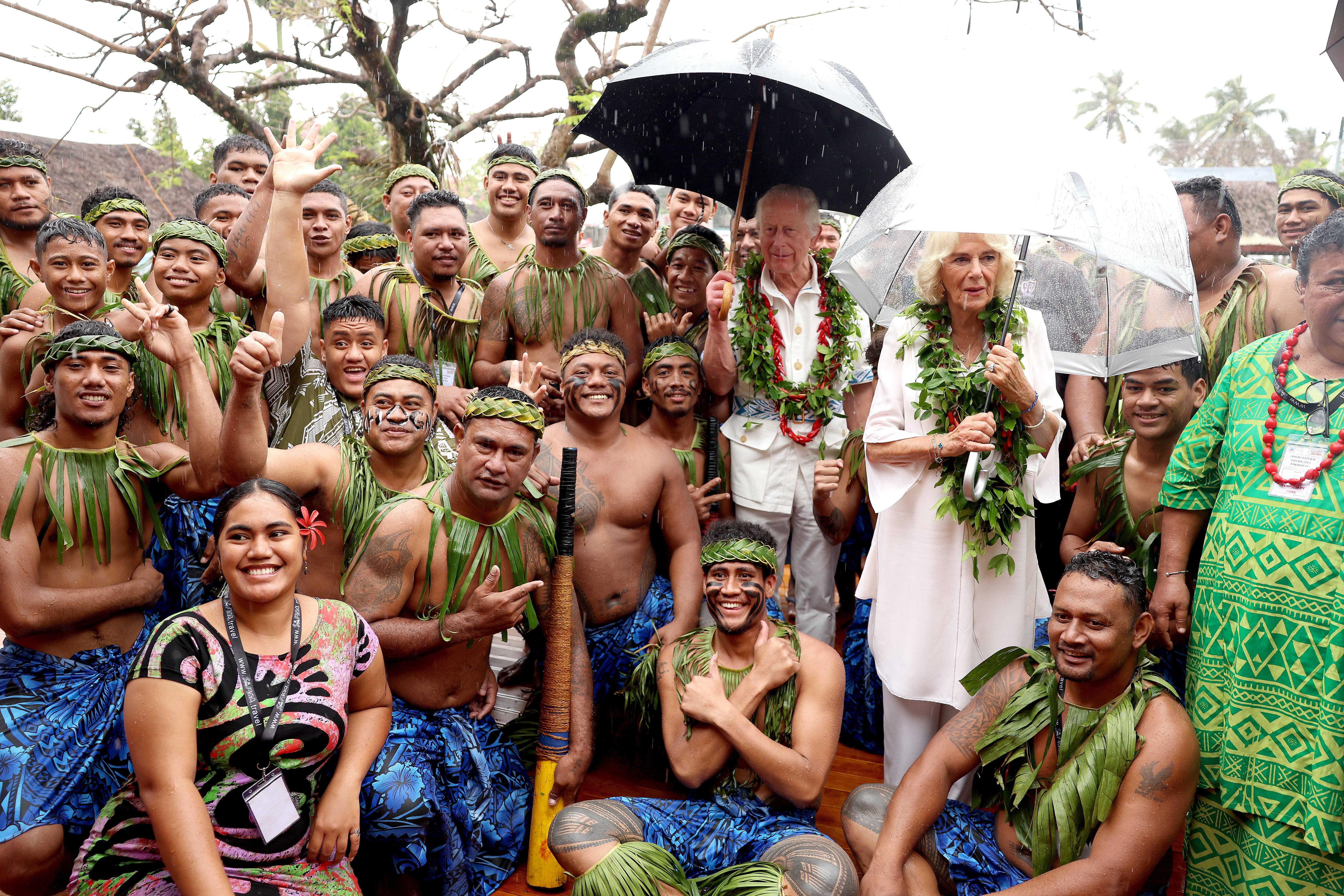 El rey Carlos y la reina Camilla posan con miembros del equipo de cricket tradicional local.